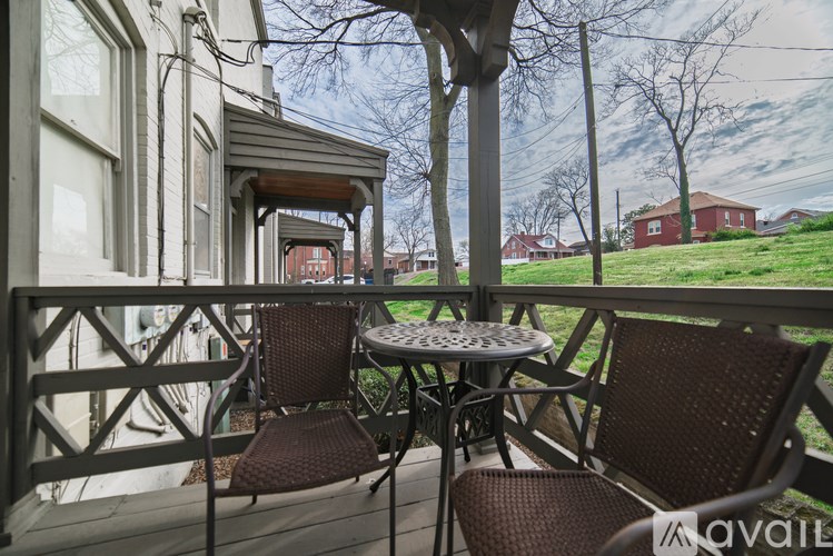 A patio with a table and chairs overlooking a grassy area.