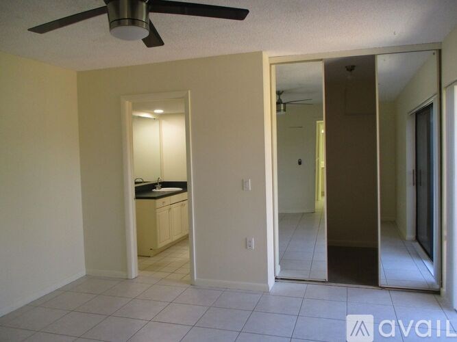 A room with a ceiling fan and a kitchen area with a sink and cabinets.