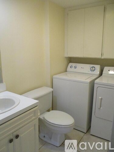 A small bathroom with a toilet, sink, and washing machine.