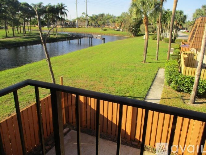A balcony overlooks a green lawn and a body of water.