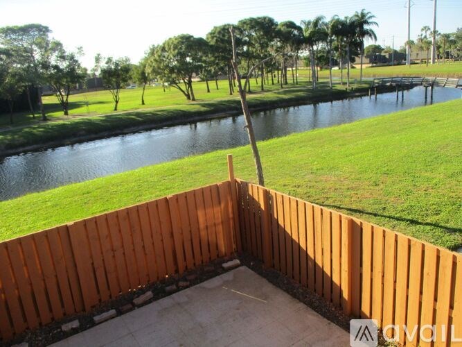 A wooden fence in the foreground with a river and trees in the background.