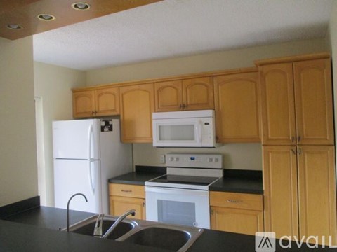 A kitchen with wooden cabinets and black countertops.
