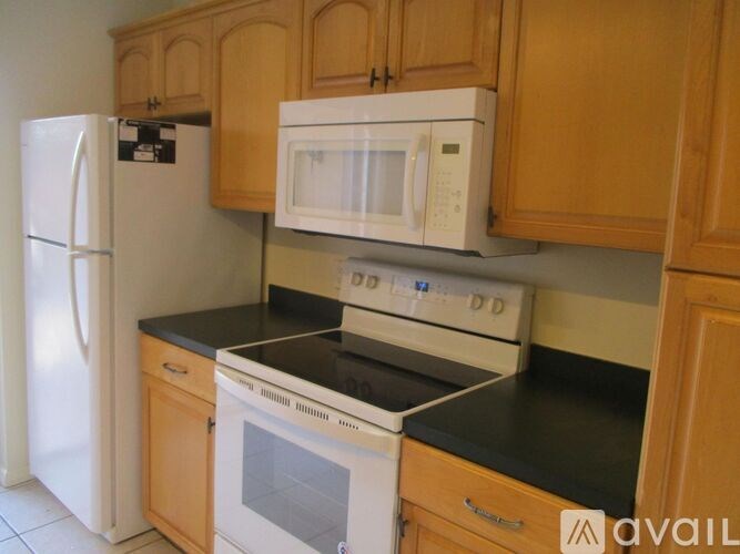 A white refrigerator and microwave are on a countertop in a kitchen.