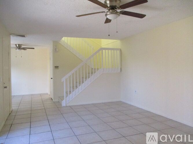 A room with a fan and a staircase.