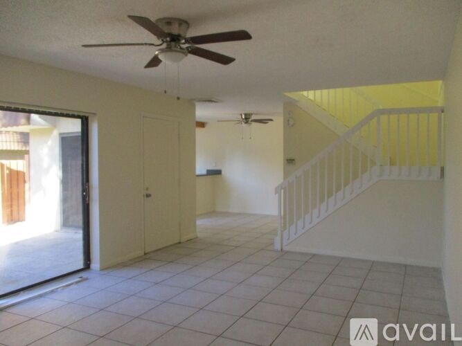 A room with a ceiling fan and a staircase.