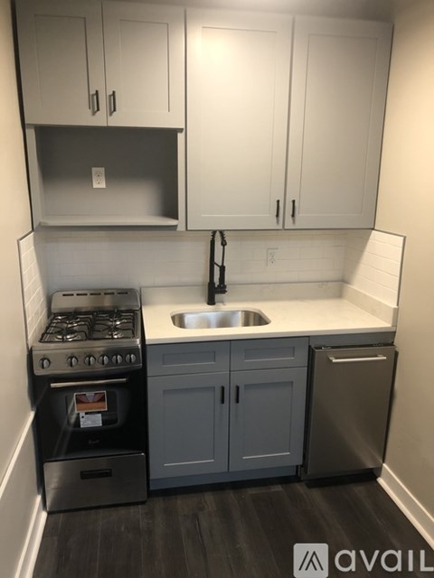A kitchen with a stove, sink, and cabinets.