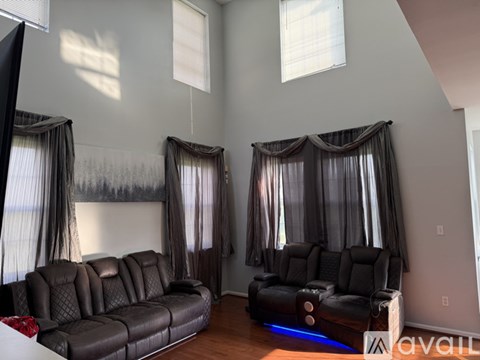 A living room with a black leather sofa and a black leather chair.