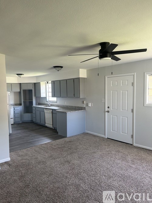 A spacious kitchen and living room with a ceiling fan.