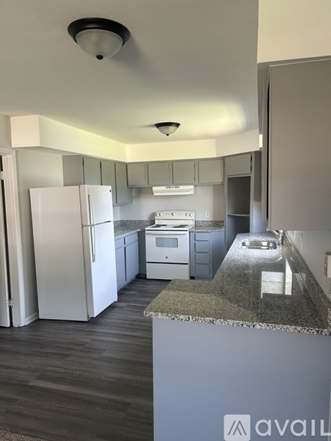 A kitchen with a white refrigerator and a granite counter top.