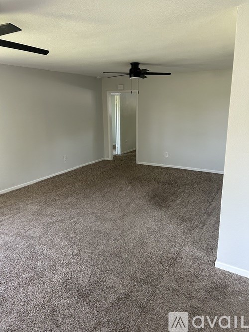 A room with a carpeted floor and a ceiling fan.
