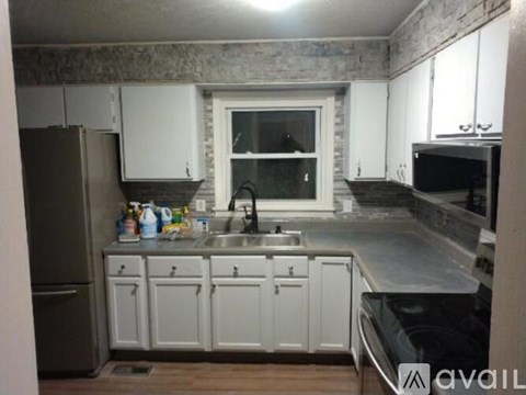 A kitchen with white cabinets and a stone wall backsplash.