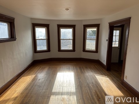 A room with wooden floors and three windows.
