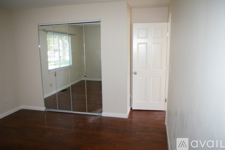 A room with a white door and a mirrored closet door.