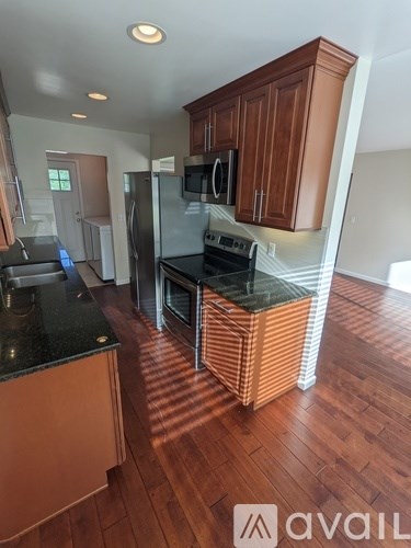 A kitchen with wooden cabinets and black countertops.