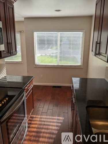 A kitchen with dark wood floors and black countertops.