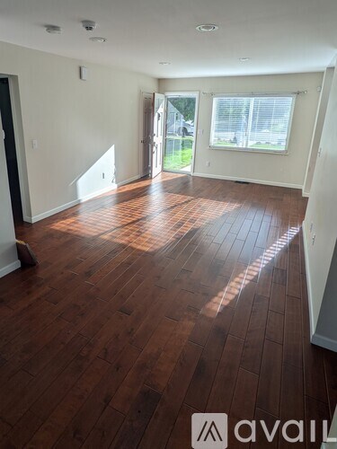 A room with wooden flooring and a window with blinds.