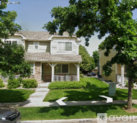 A two-story house with a front porch and a tree in front.