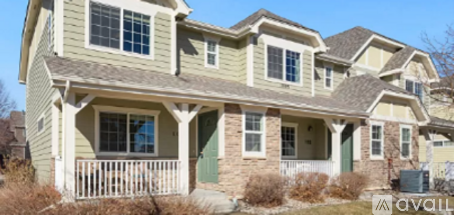 A two-story house with a porch and a green door.