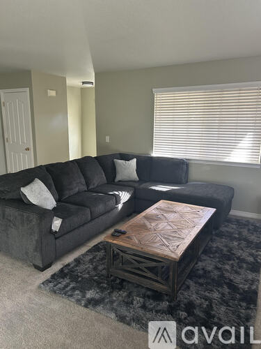 A black sectional sofa with a wooden coffee table in front of it.
