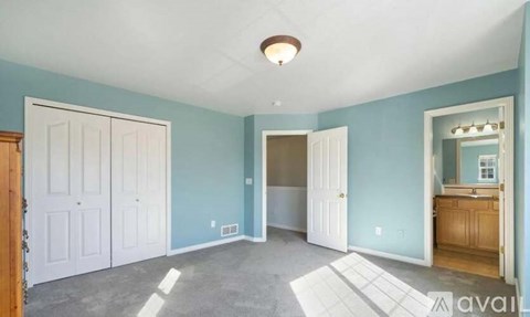 A room with a white ceiling and a light fixture, and a door on the left.