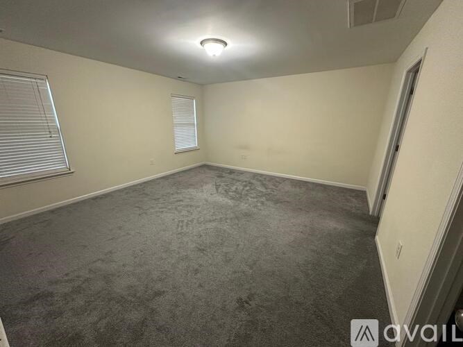 A room with a carpeted floor and a window with blinds.