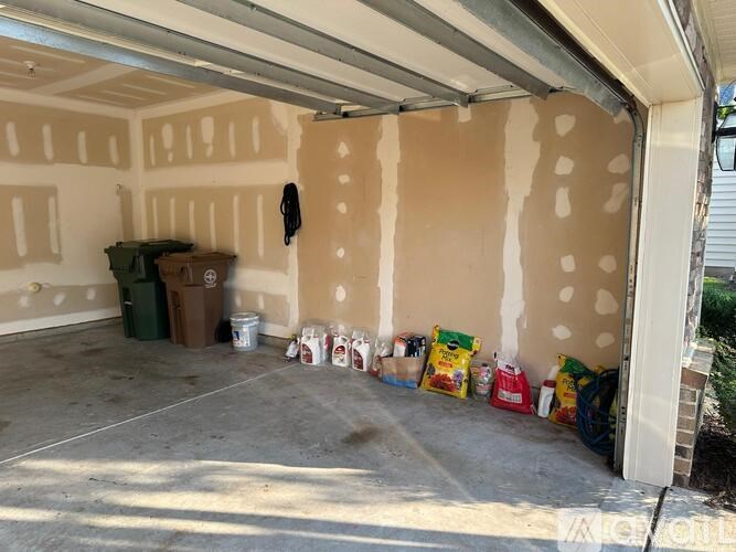 A garage with a white door and a brown wall with a lot of items on the floor.