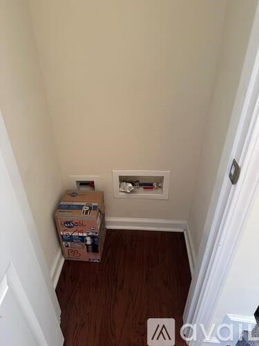 A cardboard box with the word "Foosball" on it sits on a wooden floor next to a white door.