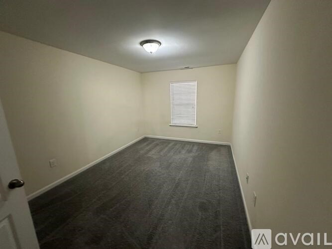 A room with a wooden floor and a window with blinds.