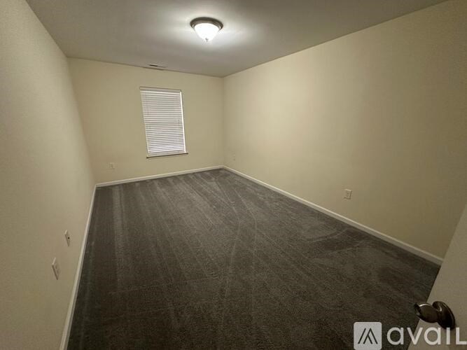 A room under construction with a green and brown trash bin, a black phone, and several cans of paint.