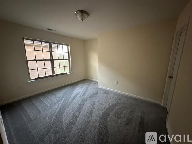 A room with a carpeted floor and a window.