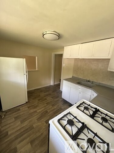 A kitchen with a white gas stove and a white refrigerator.