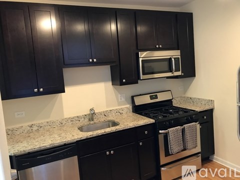 A kitchen with black cabinets and a granite countertop.