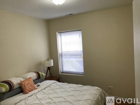 A bedroom with a bed, lamp, and window.
