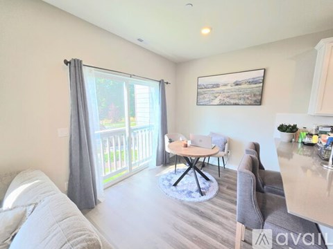 A living room with a grey couch, a round table, and a painting on the wall.