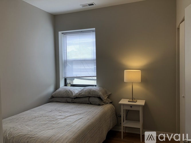 A bedroom with a bed, nightstand, and window.