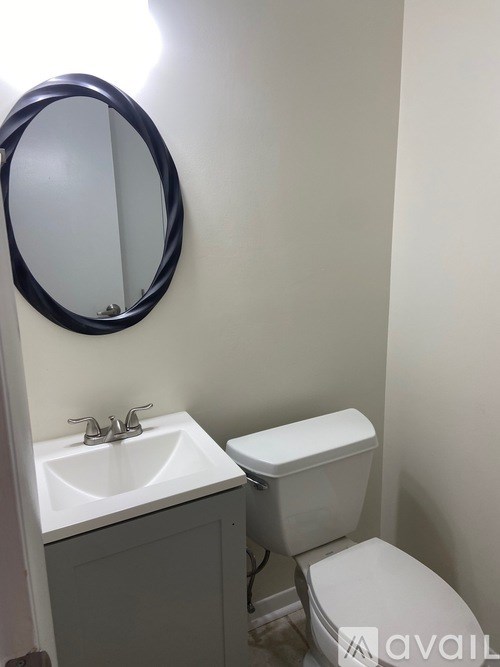 A bathroom with a toilet, sink and mirror.