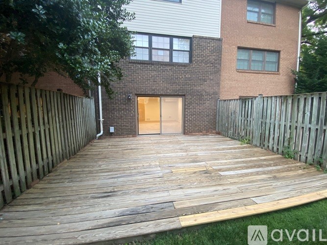 A wooden deck leads to a brick building with a closed door.