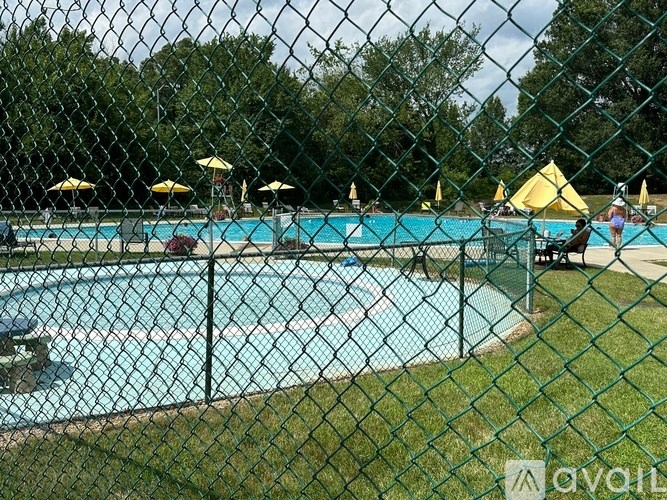 A chain link fence surrounds a pool with a blue tinted water.