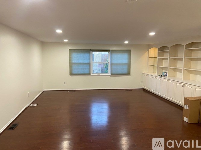 A room with wooden flooring and a window with blinds.