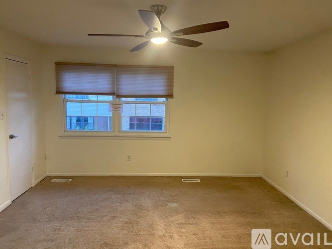A room with a ceiling fan and a window with blinds.