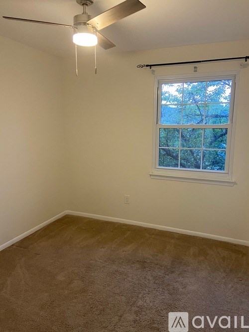 A room with a ceiling fan and a window with blinds.