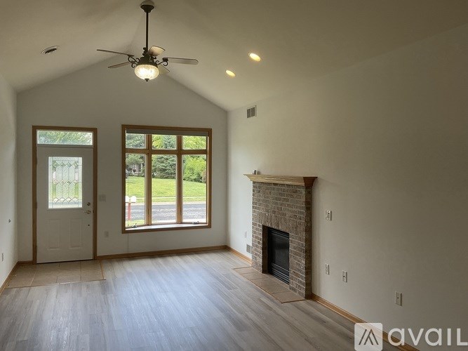A spacious room with a fireplace and a ceiling fan.
