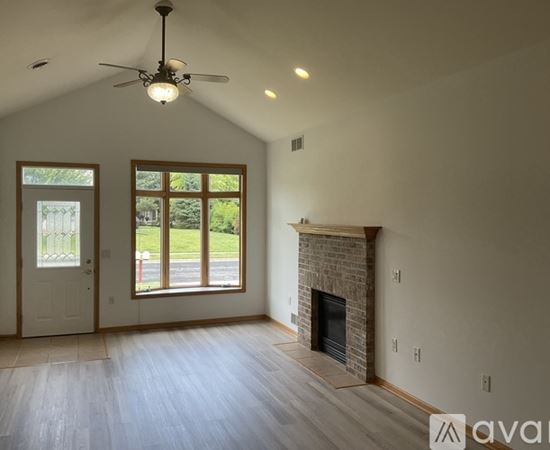 A spacious room with a fireplace and a ceiling fan.