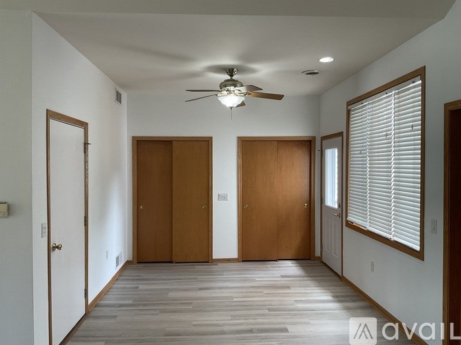 A room with a ceiling fan and wooden floors.