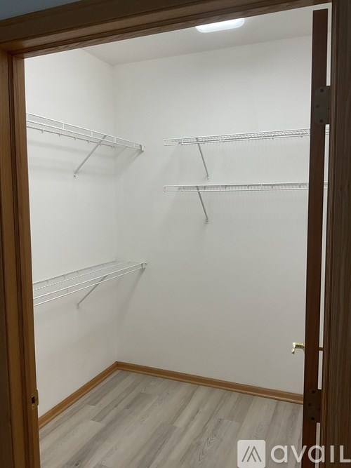 A white closet with wooden floors and a door.