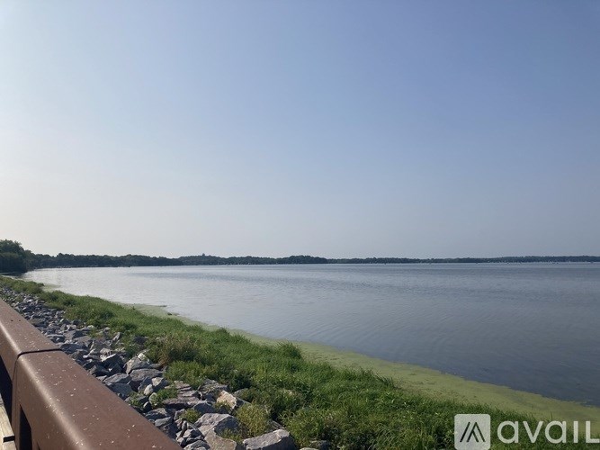 A body of water with a rocky shore and a railing.