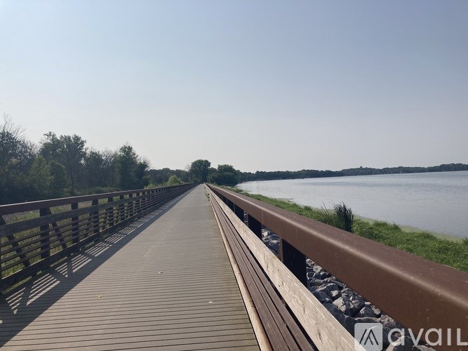 A wooden walkway leads to a body of water with trees in the background.