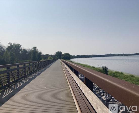A wooden walkway leads to a body of water with trees in the background.