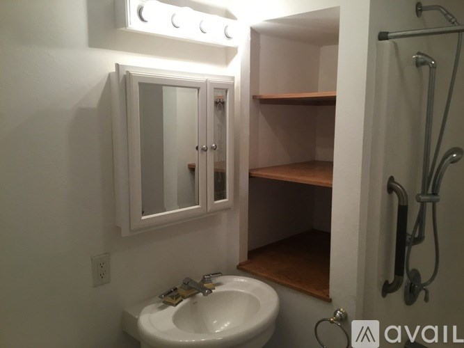 A bathroom with a white sink and a mirror with lights above it.