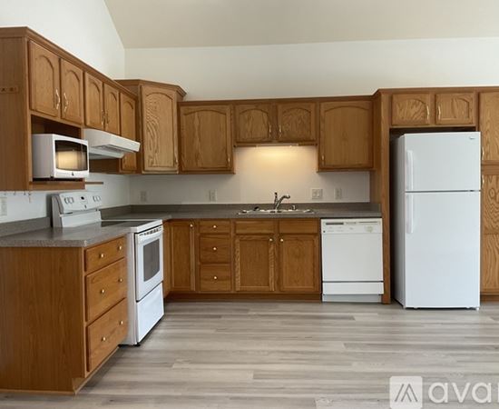 A kitchen with wooden cabinets and white appliances.